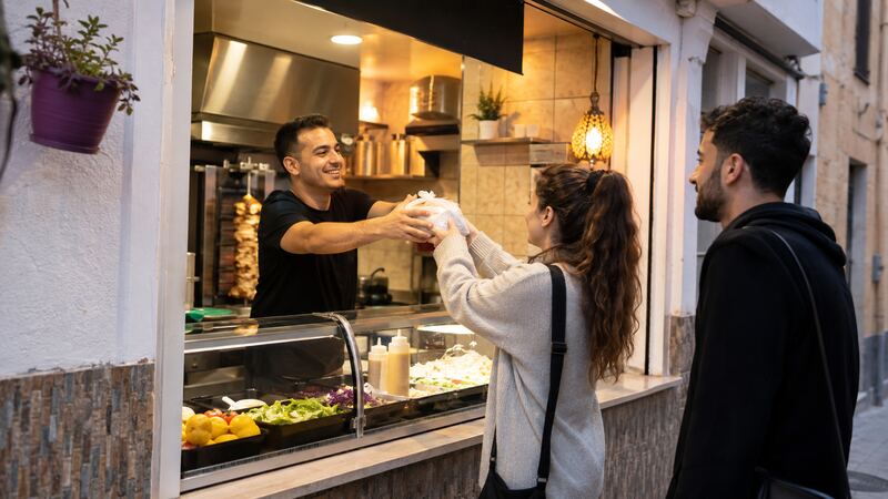 Propietario de un local turco entregando comida para llevar en un barrio de Jerez