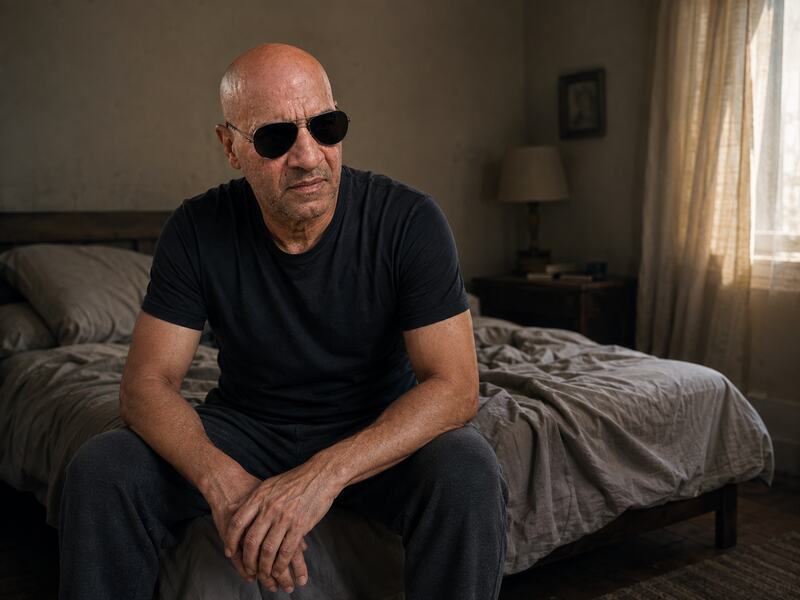Mel sentado en la cama durante un bajón emocional, con el rostro visible y gafas oscuras