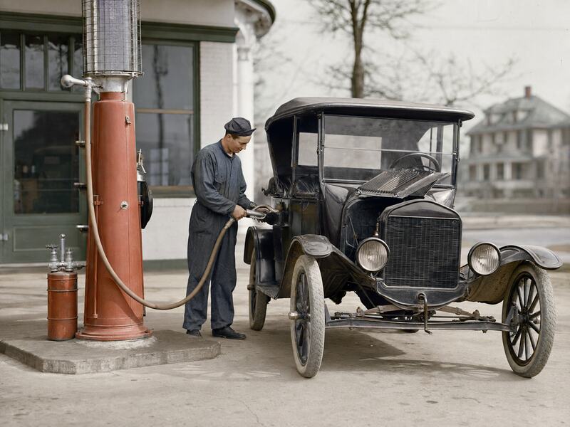 Automóvil repostando gasolina con plomo en una estación de servicio de los años veinte